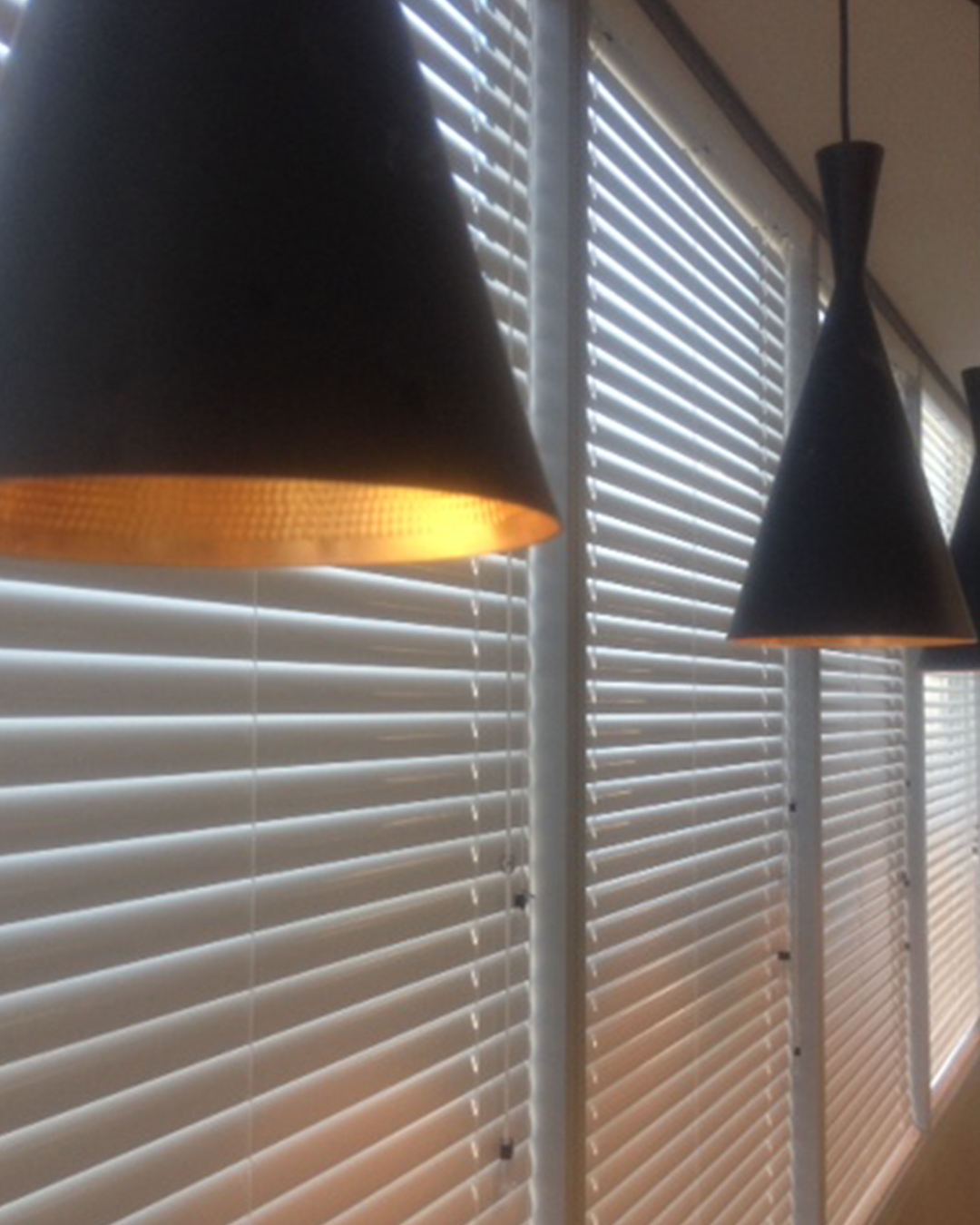 A partially open set of aluminum blinds, showcasing their adaptability in regulating sunlight and bringing a contemporary element to interior design.