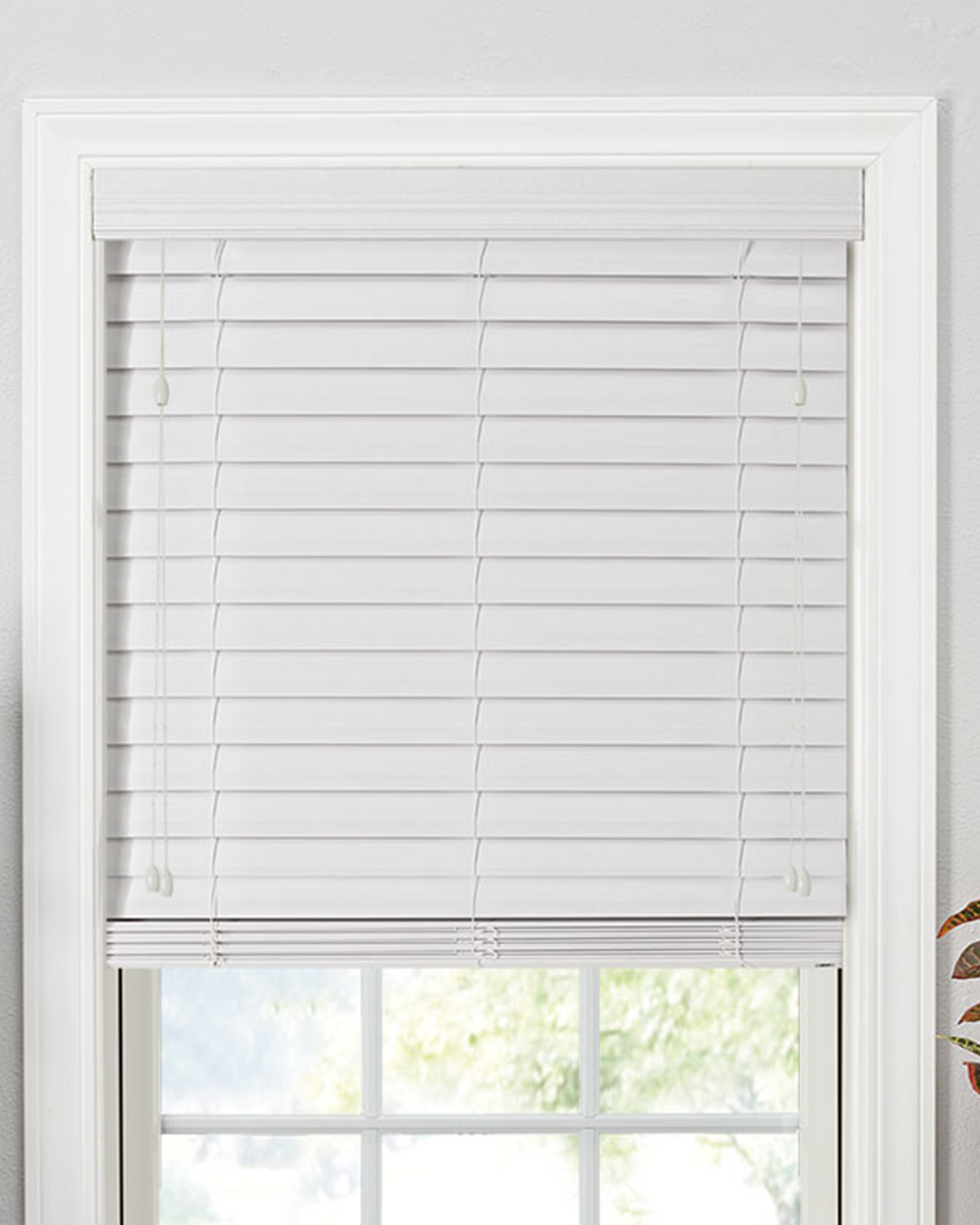 A window is elegantly covered with white composite blinds, giving the space a crisp, contemporary look.