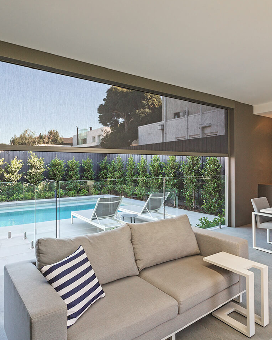 A zip screen by a swimming pool is intended to provide privacy and protection from the sun in an outdoor living space.